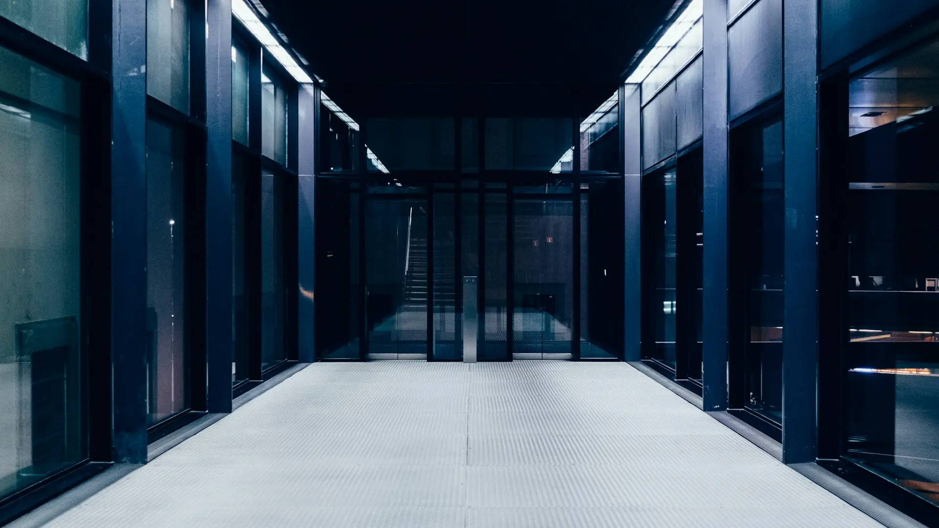 a long hallway with glass doors leading to another room